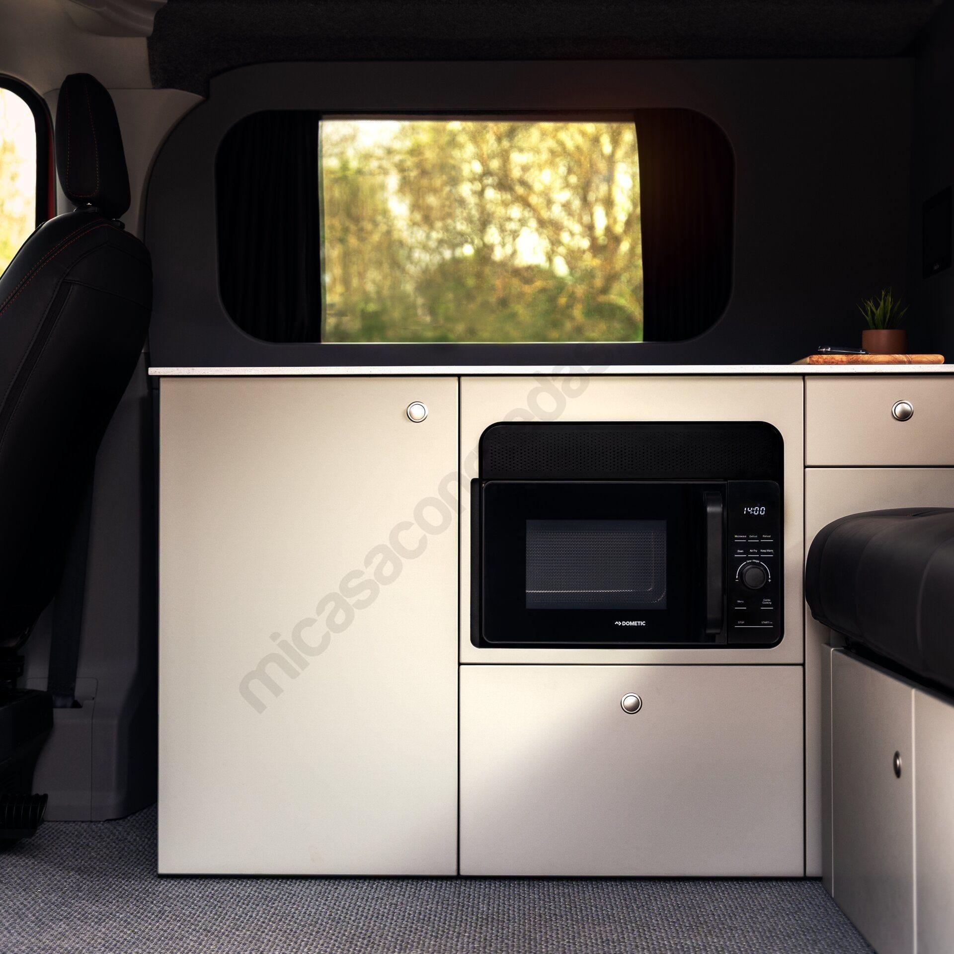Micro-ondes Dometic AC MWAO 240 installé dans le meuble de cuisine d’un van aménagé.