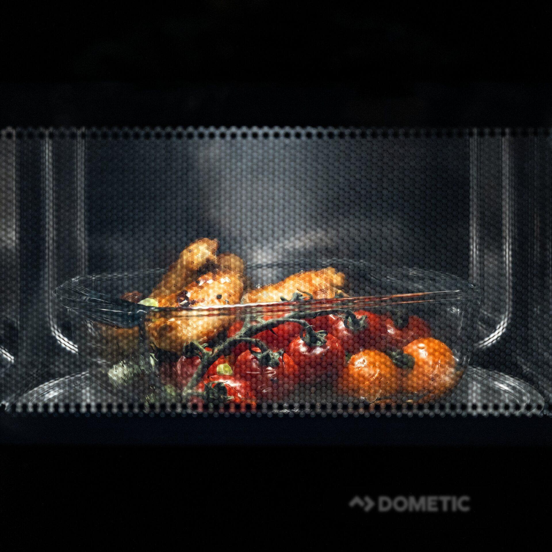 Poulet et tomates dans un plat en verre à l’intérieur du Dometic AC MWAO 240.